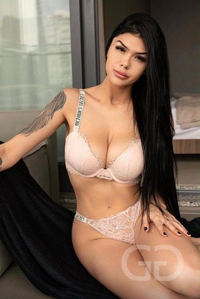 Angel seated in pale pink lace lingerie, long straight black hair