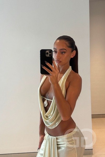 Indie, English escort, in a gold draped halter top and skirt