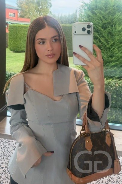 Latin escort London Sophie with long brunette hair, mirror selfie with a designer handbag