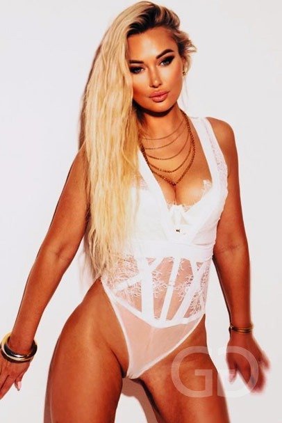 Alice, South Kensington escort, in a white lace bodysuit and layered gold chains