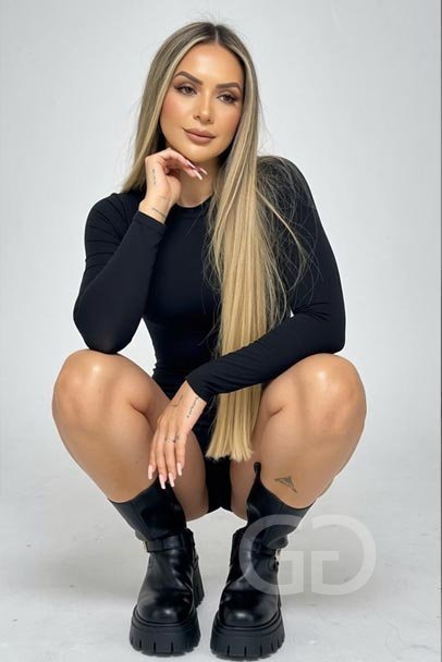 Victoria crouching in a black long-sleeved dress and chunky boots