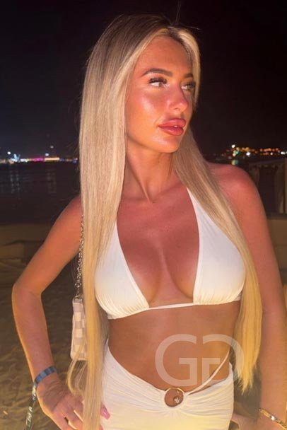 Alana, English escort, in a white bikini top on a waterfront at night