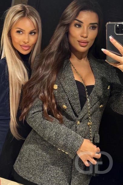 Mirror selfie of Laura with a brunette friend in a tweed blazer