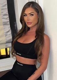 Alva thumbnail - in a black crop top, long brunette hair